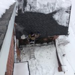 Commercial ice dam removal project. Man on ladder ice dam steaming